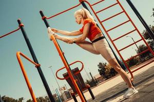 schöne Blondine beim Stretching auf dem Spielplatz foto