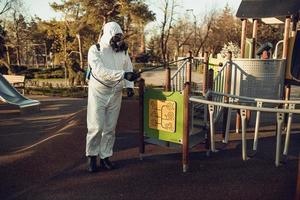 reinigung und desinfektion auf dem spielplatz im stadtkomplex inmitten der coronavirus-epidemieteams zur desinfektionsbemühungen infektionsprävention und bekämpfung von epidemieschutzanzug und maske foto