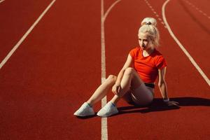 entzückende Blondine sitzt auf einer Joggingstrecke foto