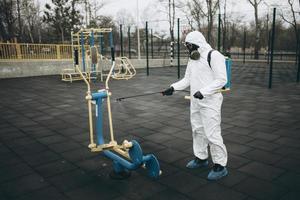 reinigung und desinfektion auf dem spielplatz im stadtkomplex inmitten der coronavirus-epidemieteams zur desinfektionsbemühungen infektionsprävention und bekämpfung von epidemieschutzanzug und maske foto