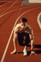 junger Mann mit athletischem Körper, der sich zum Laufen bereit macht foto