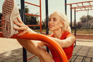 schöne Blondine beim Stretching auf dem Spielplatz foto