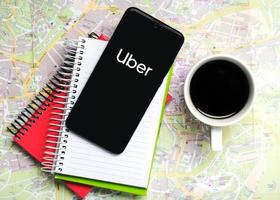 uber-anwendungssymbol auf schwarzem bildschirm des smartphones mit notizbüchern und einer tasse kaffee foto