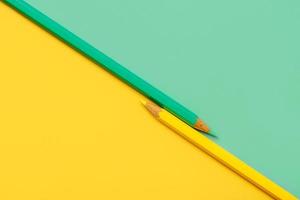Gelber und grüner Bleistift auf gelbem und grünem Papierhintergrund mit Kopierraum foto