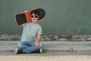 glückliches Kind mit Skateboard und Sonnenbrille foto