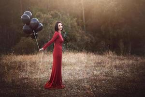 nachdenkliche Frau mit Luftballons im Feld foto