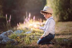 verträumter Junge, der auf dem Feld sitzt foto