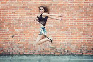 junge lächelnde Frau, die in die Luft springt foto