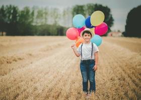 glückliches Kind mit Luftballons auf dem Feld foto