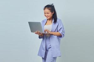 Porträt einer lächelnden jungen asiatischen Frau, die Laptop isoliert auf weißem Hintergrund betrachtet foto