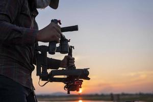 Filmemacher oder Ersteller von Inhalten, die eine Stabilisator-Gimbal-Kamera verwenden, nehmen Videomaterial am Standort im Freien auf foto