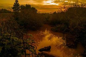 Fluss bei ruhigem Sonnenuntergang. die sonne ist von wolken verdeckt foto