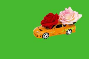 Spielzeugauto mit Rosen auf grünem Hintergrund foto