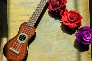 rote Rose auf einem lila Gitarren-Ukulele-Hals und Griffbrett. foto