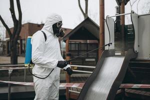 reinigung und desinfektion auf dem spielplatz im stadtkomplex inmitten der coronavirus-epidemieteams zur desinfektionsbemühungen infektionsprävention und bekämpfung von epidemieschutzanzug und maske foto