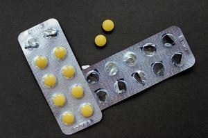 Pillen in einer Blisterpackung, eine leere Blisterpackung und zwei Pillen separat auf schwarzem Hintergrund foto