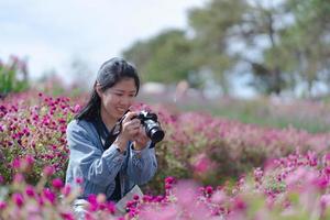 reife asiatische frau, die kamera verwendet, um fotos von blumen bei sonnenuntergang zu schießen