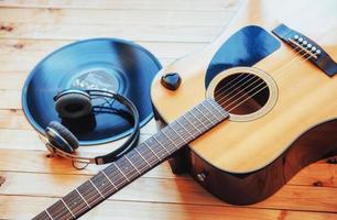 klassische gitarre mit kopfhörern auf einem hölzernen hintergrund foto