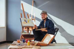 Entworfen vom Künstler Mann, der sein Meisterwerk fertigstellt, hält einen Pinsel in der Hand. foto