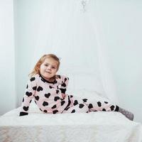 Kind im weichen, warmen Schlafanzug, der im Bett spielt foto