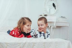 Kind im weichen, warmen Schlafanzug, der im Bett spielt foto