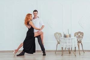 junge schöne Frau in einem schwarzen Kleid und ein Mann im weißen Hemd tanzen. foto