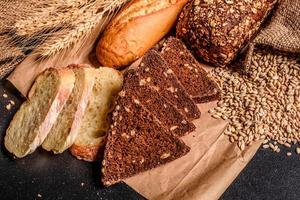 Schönes frisch gebackenes Brot mit Weizenkörnern auf dunklem Betonhintergrund foto