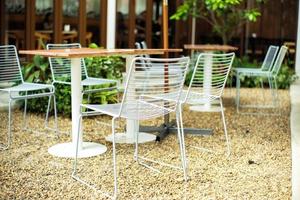 Closeup Gruppe von modernen Metallstühlen und Tisch in weißer Farbe im Café im Freien foto