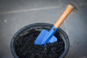 Schaufel auf Anbauboden in schwarzem Topf zum Pflanzen, Vorbereitung des Bodens zum Pflanzen von Pflanzen oder Blumen in Töpfen foto