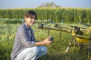 Junger intelligenter Landwirt, der Drohnen kontrolliert, die Düngemittel und Pestizide über Ackerland sprühen, hochtechnologische Innovationen und intelligente Landwirtschaft foto