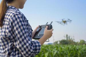 Junger intelligenter Landwirt, der Drohnen kontrolliert, die Düngemittel und Pestizide über Ackerland sprühen, hochtechnologische Innovationen und intelligente Landwirtschaft foto