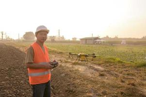 Männlicher Ingenieur, der Drohnen kontrolliert, die Düngemittel und Pestizide über Ackerland sprühen, High-Tech-Innovationen und intelligente Landwirtschaft foto