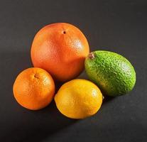 Köstliche frische Orange, Grapefruit, Avocado, Zitrone isoliert auf schwarzem Hintergrund. foto