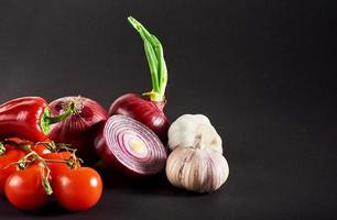 Zwiebel und Knoblauch und Peperoni und Tomaten auf schwarzem Hintergrund isoliert. foto