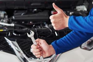 Hände des Automechanikers mit Schraubenschlüssel in der Garage foto