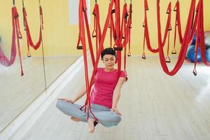 junge schöne frau, die yoga-fliege mit einer hängematte im studio praktiziert. foto