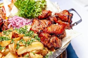 gemischtes grillfleisch gebratenes gemüse und gegrillte lachsfischfilets dekoration in warmer schale. Verschiedene köstliche gegrillte Kebabs, serviert mit Kräutern auf einer Platte. restaurant menü grillplatte bbq party mahlzeit foto