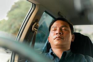 Ein Mann benutzt sein Telefon während der Fahrt und schläft während der Fahrt ein. foto