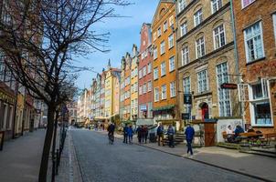 danzig, polen, 15. april 2018 leute gehen entlang piwna straßenpflaster im alten historischen stadtzentrum mit fassade von schönen typischen bunten häusern gebäuden und bäumen foto