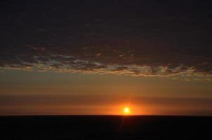 Sonnenuntergang mit Strahlen am Meer foto