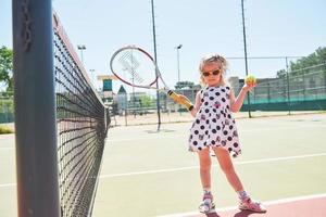 glückliches kleines Mädchen, das Tennis spielt foto