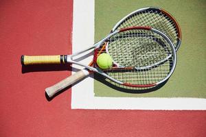 ein Tennisschläger und ein neuer Tennisball auf einem frisch gestrichenen Tennisplatz foto