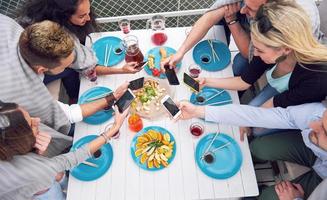 Glückliche junge Freunde saßen an einem Tisch und machten ein Picknick im Freien foto