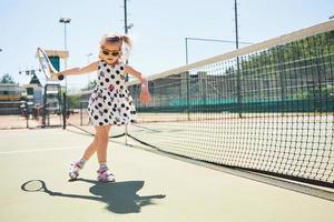 süßes mädchen, das tennis spielt und für die kamera posiert foto