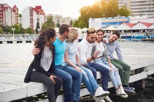 Gruppe glücklicher junger Freunde auf dem Pier, Spielfreude schafft emotionales Leben foto