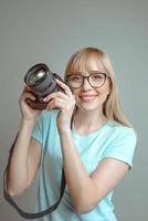 Blonde, stilvolle, fröhliche Fotografin mit Brille und Fotokamera. hobby, arbeit, schießkonzept foto