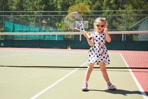 süßes mädchen, das tennis spielt und für die kamera posiert foto