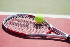 ein Tennisschläger und ein neuer Tennisball auf einem frisch gestrichenen Tennisplatz. foto