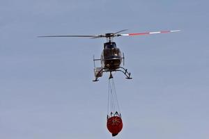 Hubschrauber, der Löschwasser transportiert foto