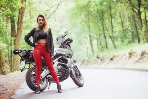 Ein attraktives sexy Mädchen auf einem Sportmotorrad, das draußen posiert foto